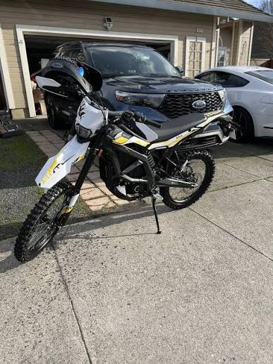 Surron electric dirt bike parked in a driveway